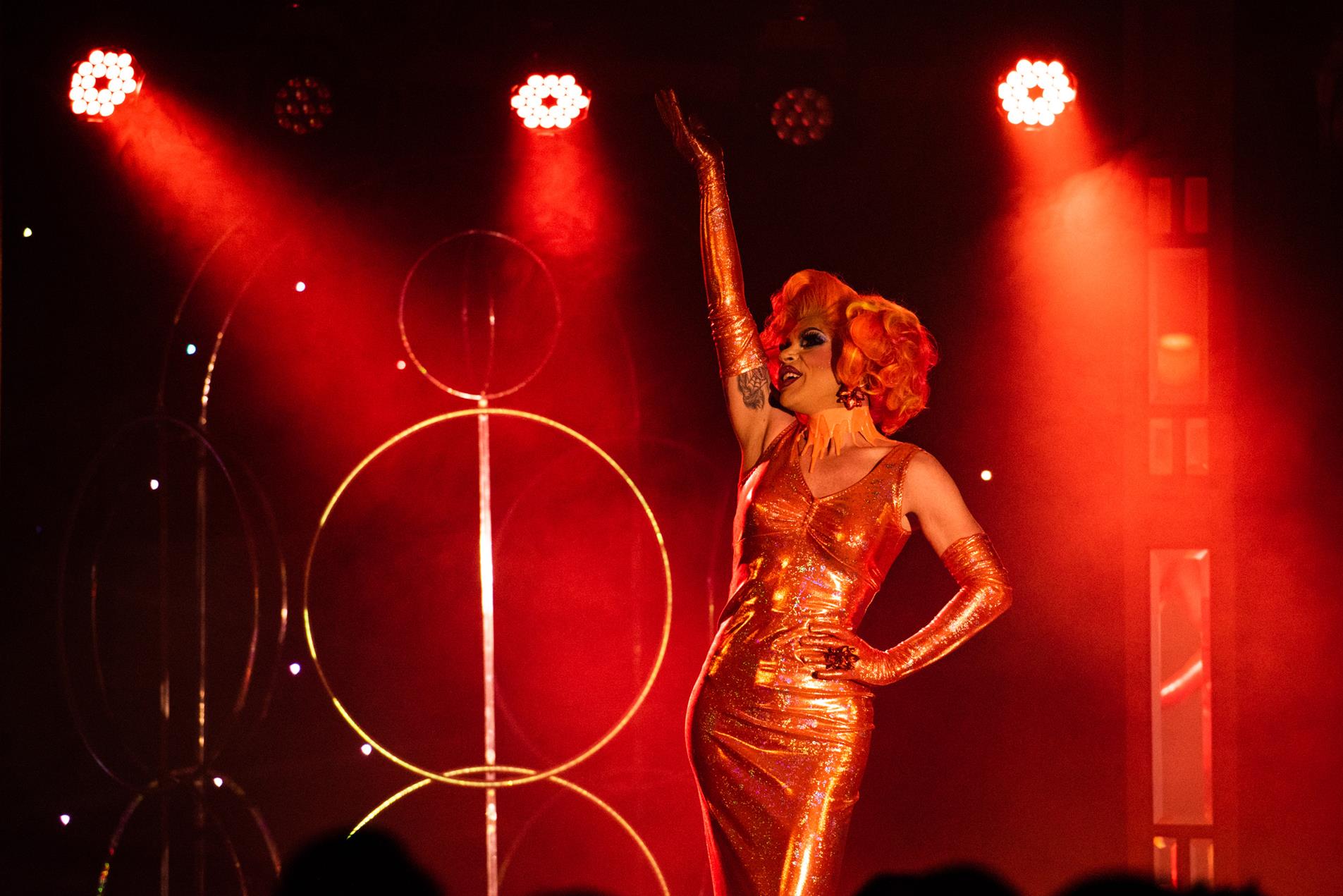 An artist wearing a vibrant orange dress performing onstage.