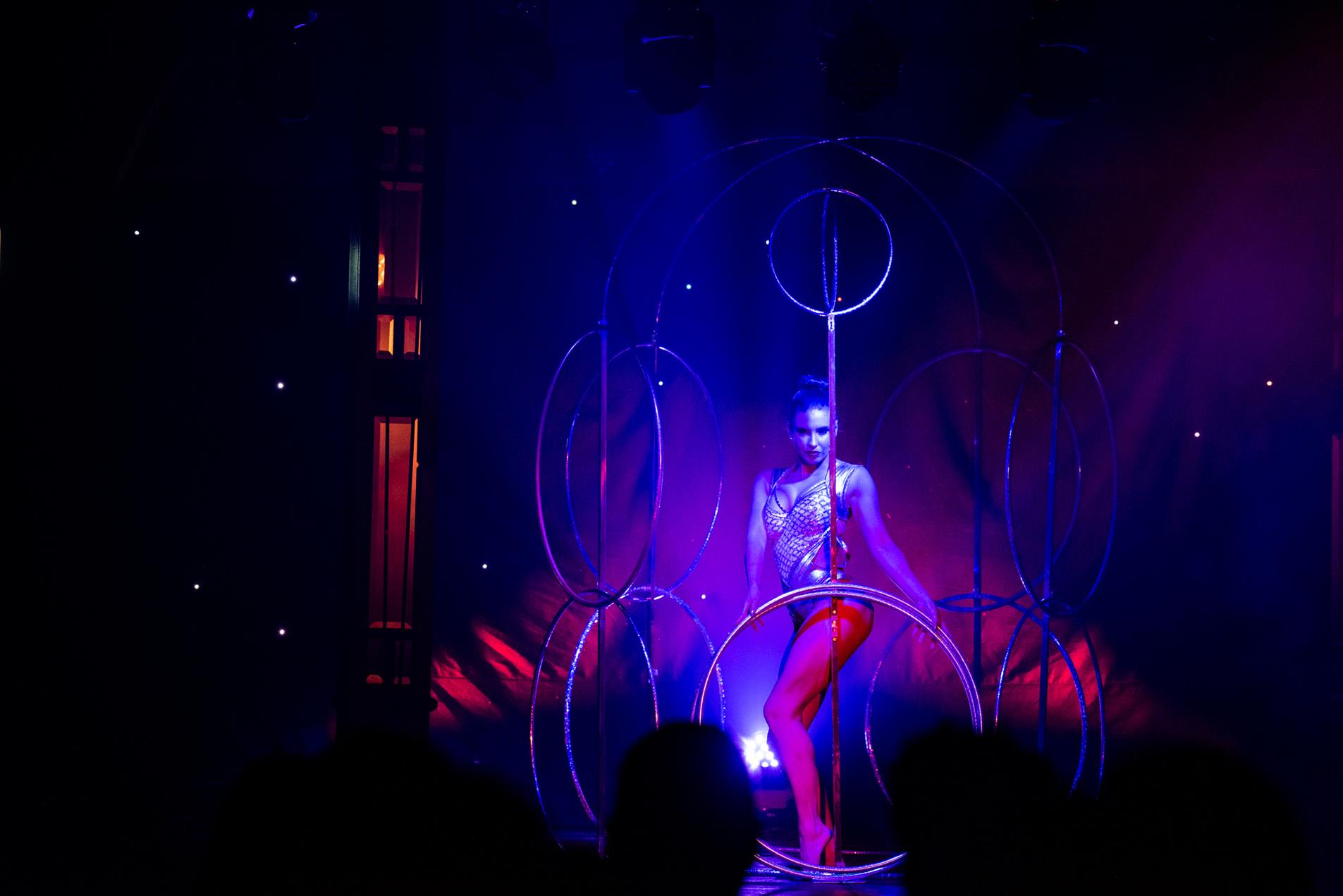 A female performer on stage in a cage of hoola hoops.