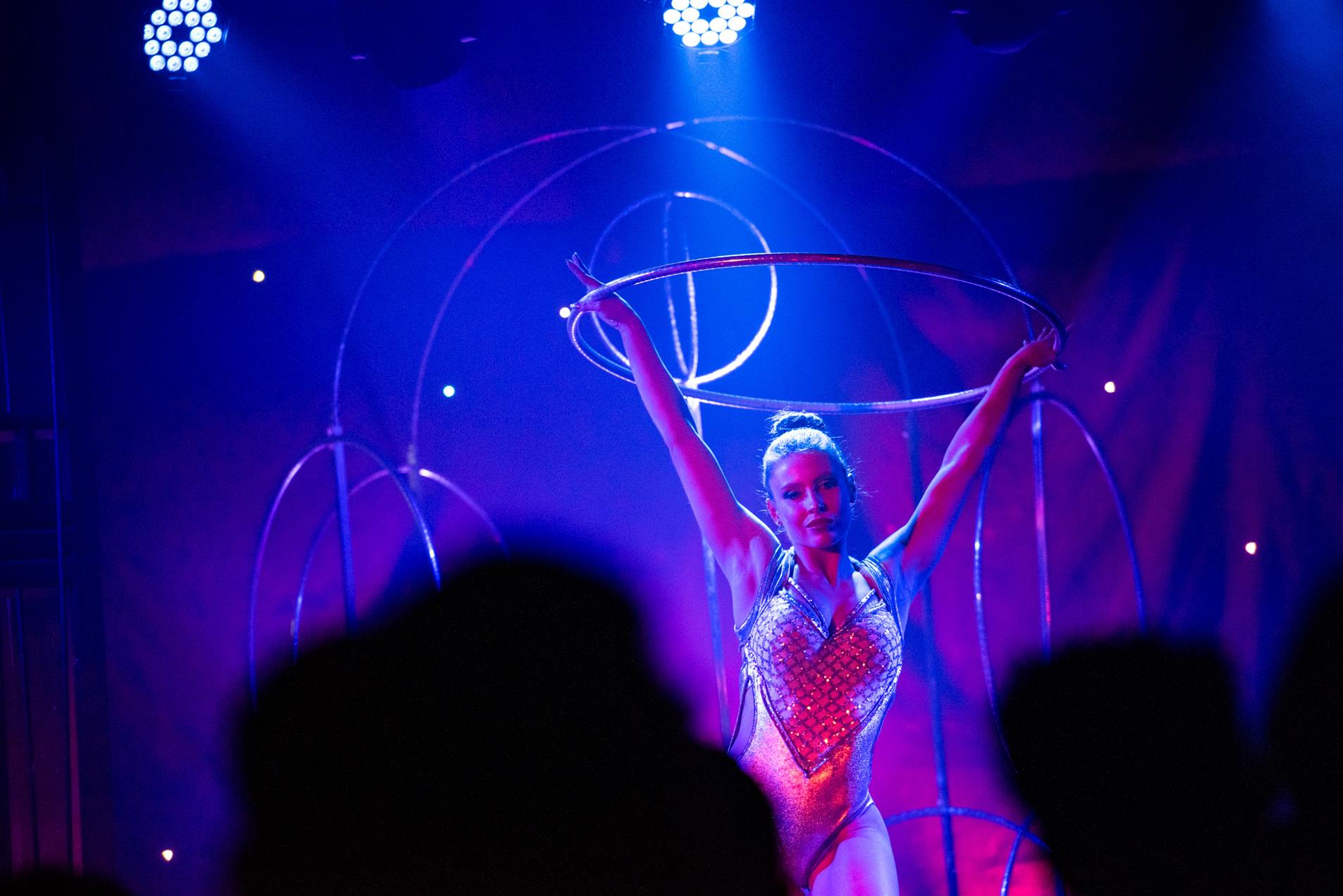 A female performer on stage holding a hoola hoop.