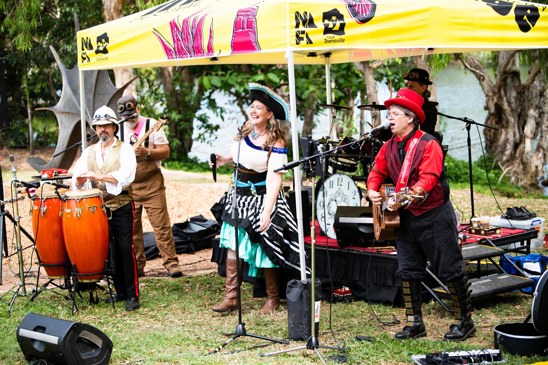 A band performing under a colourful tent at an outdoor event.