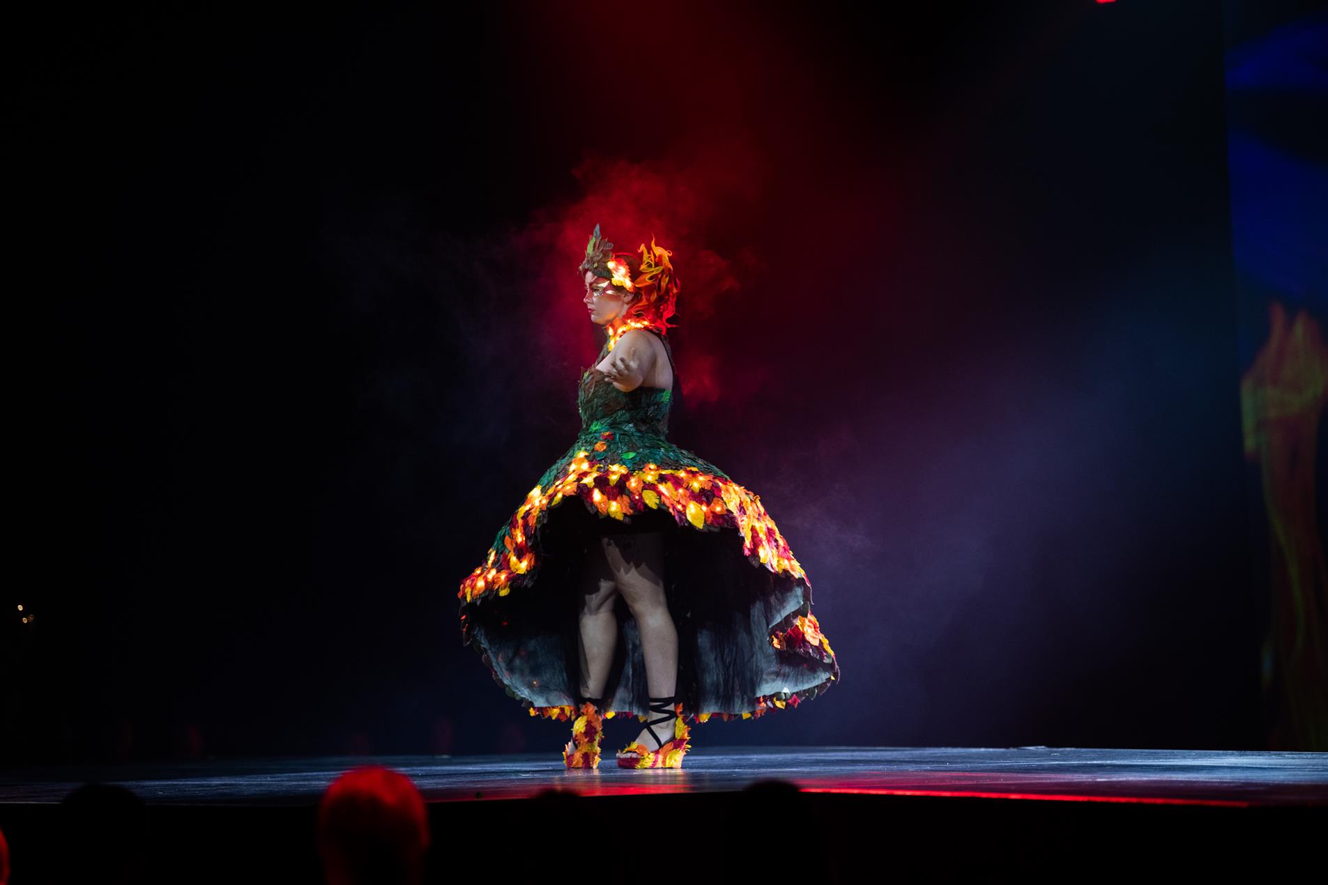 A female model wearing a fiery dress on stage.