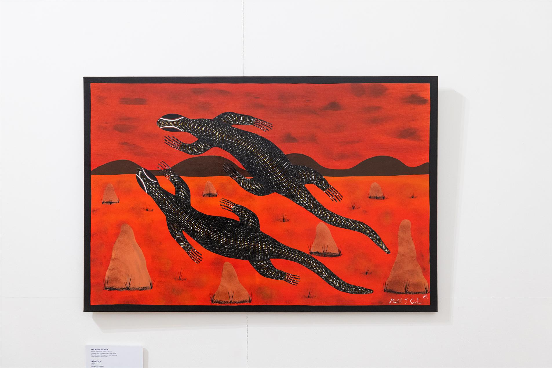 Two animals on a red desert background painted onto a canvas in a gallery.