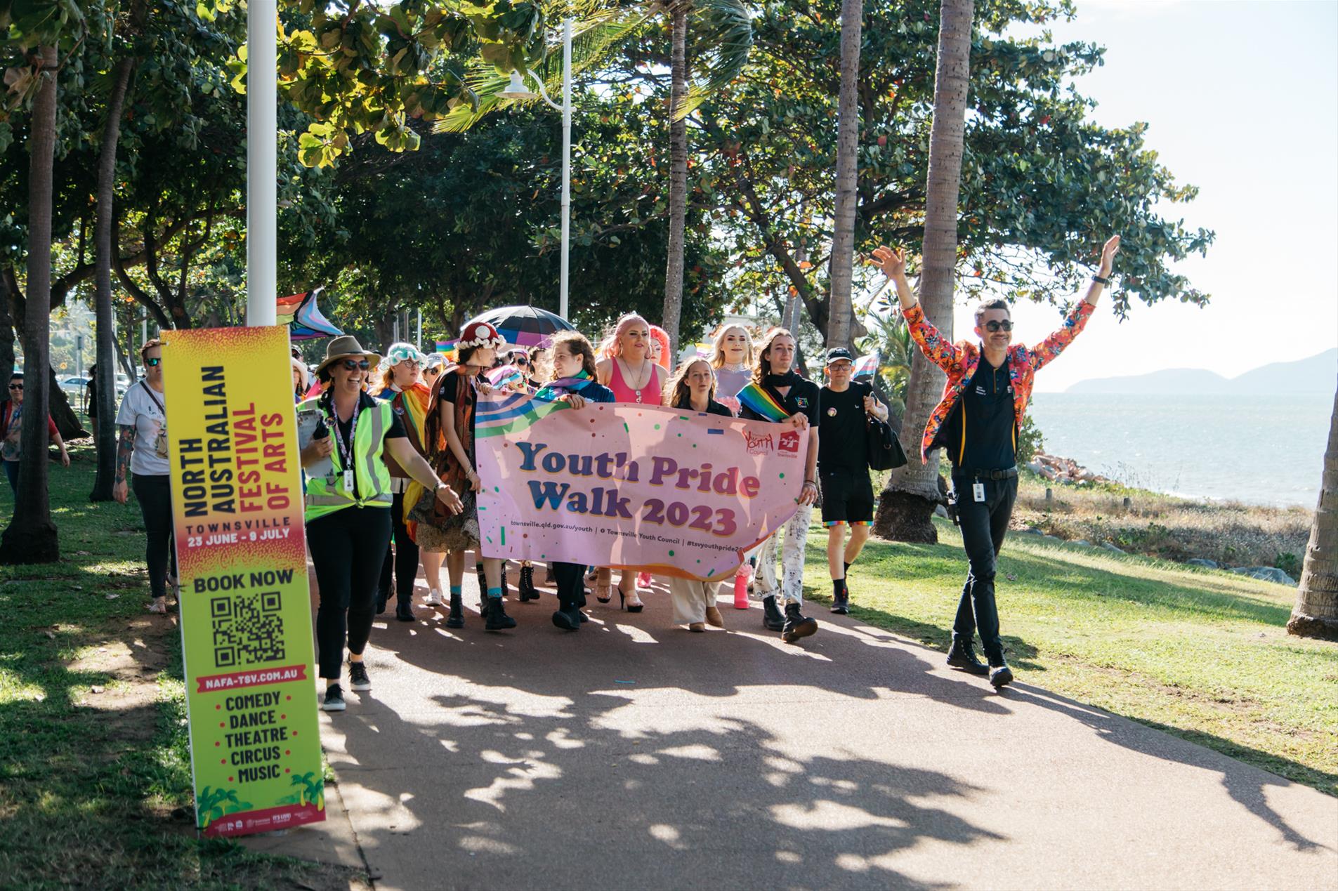 A group of people wearing colourful clothes holding a banner.