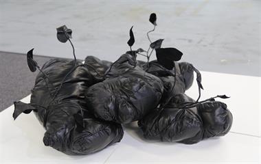 An artwork displayed in a gallery made from a type of black material.