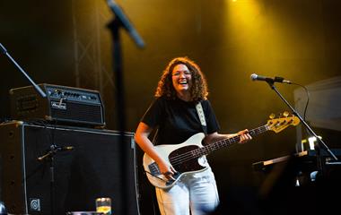 A female artist playing the guitar on stage.