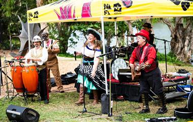 A band performing under a colourful tent at an outdoor event.