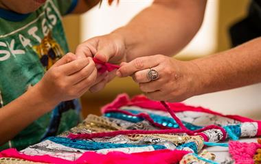 A woman teaching a child to make a dreamcatcher