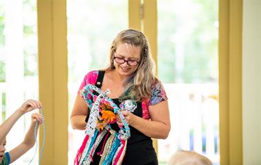 A woman holding a colourful dreamcatcher.