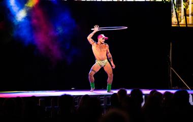 A male artist performing on stage with a hoola hoop.