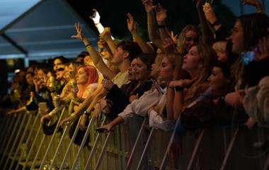 A standing crowd singing at a music festival.