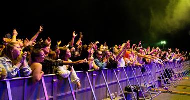 A large crowd singing at a music festival.