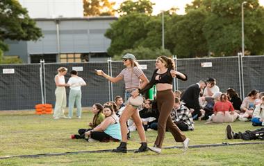 Two females walking through a crowd of people at a music festival.