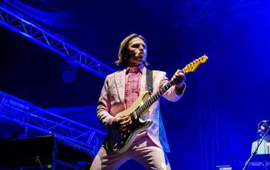 A male artist playing guitar on stage.