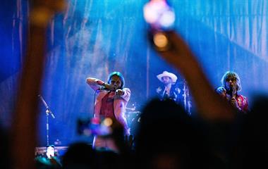 Two male artists singing into microphones.