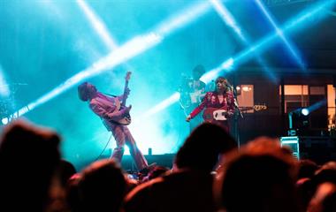 Three male artists playing guitar on stage.